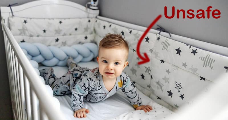 Baby in cot with unsafe crib bumpers