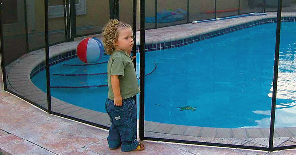 Child being kept out of swimming pool by a pool safety fence